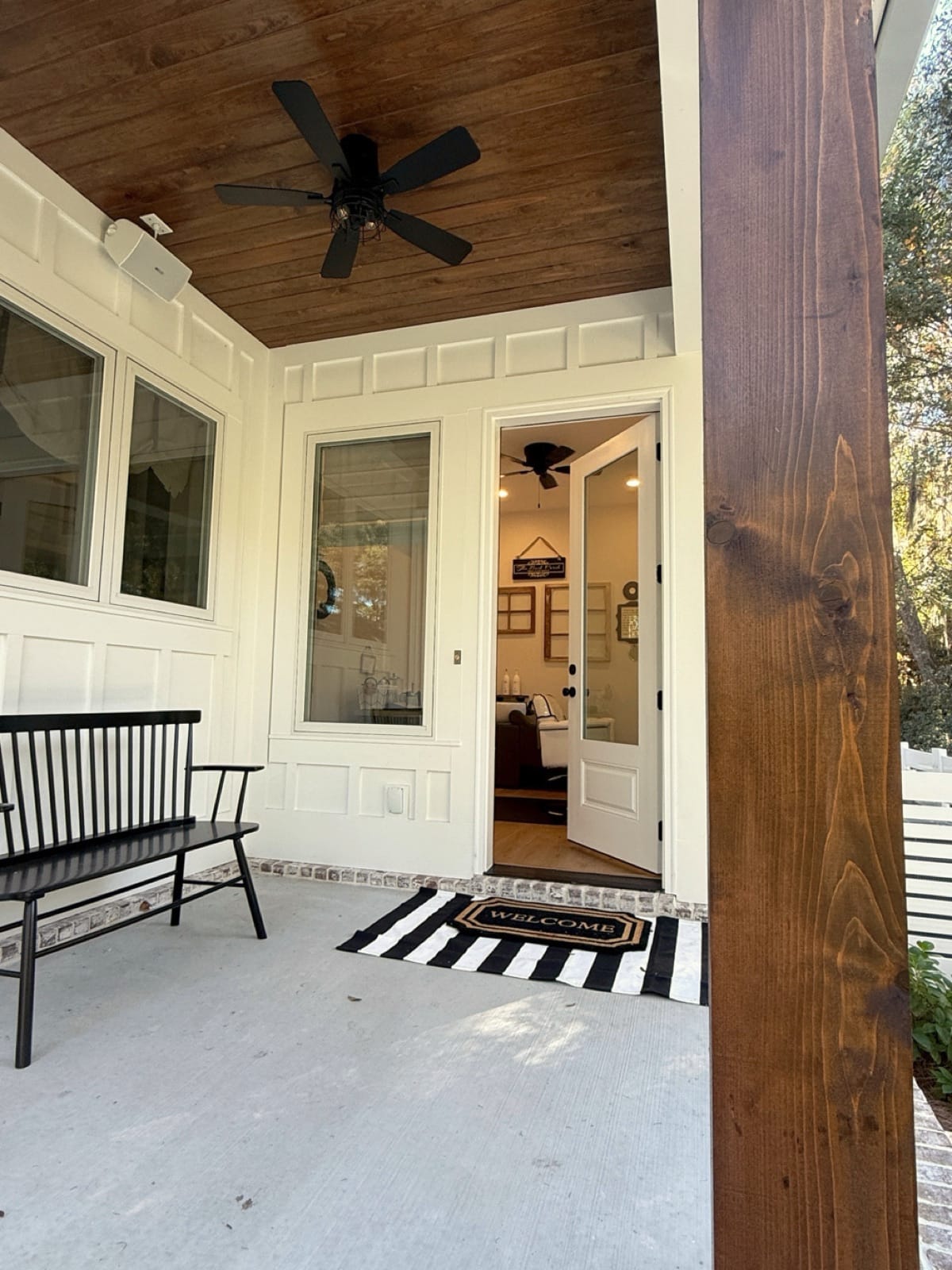 The salon's back porch with a black bench, striped rug, and welcome mat at the door