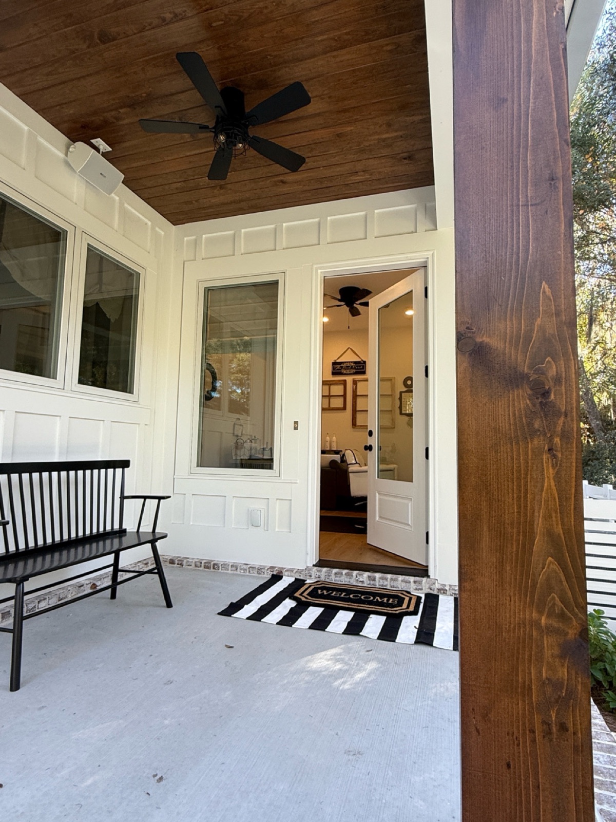 The salon's back porch with a black bench, striped rug, and welcome mat